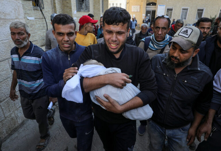 A man carries the body of Palestinian baby Ahmed Erheem, who medics said was killed in an Israeli strike, in Gaza City