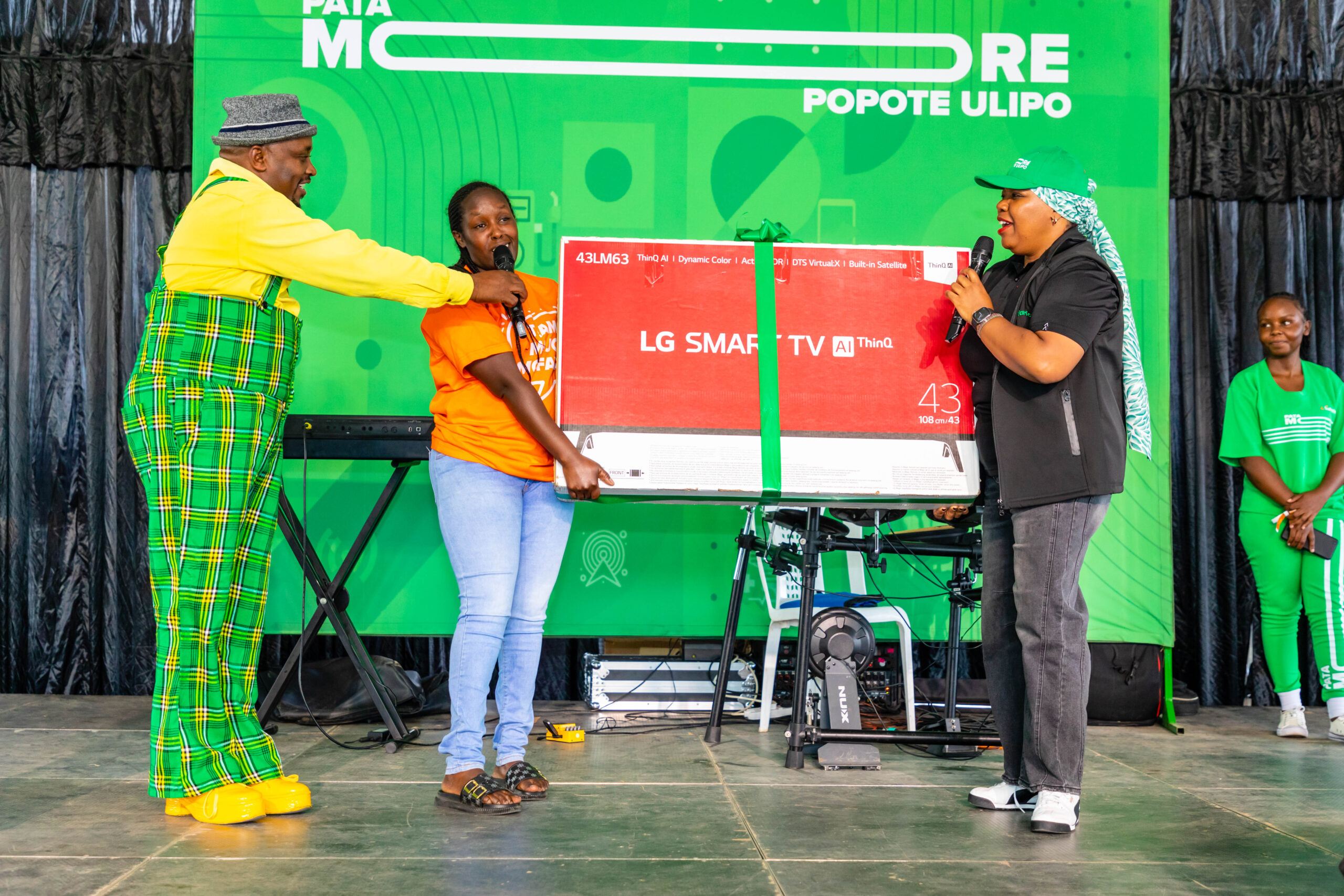 Fawzia Ali-Chief Consumer Officer if safaricom PLC(R) presenting a smart Tv to one of the ampaign winners during PATA MORE launch in Nakuru-Photo courtesy-Safaricom